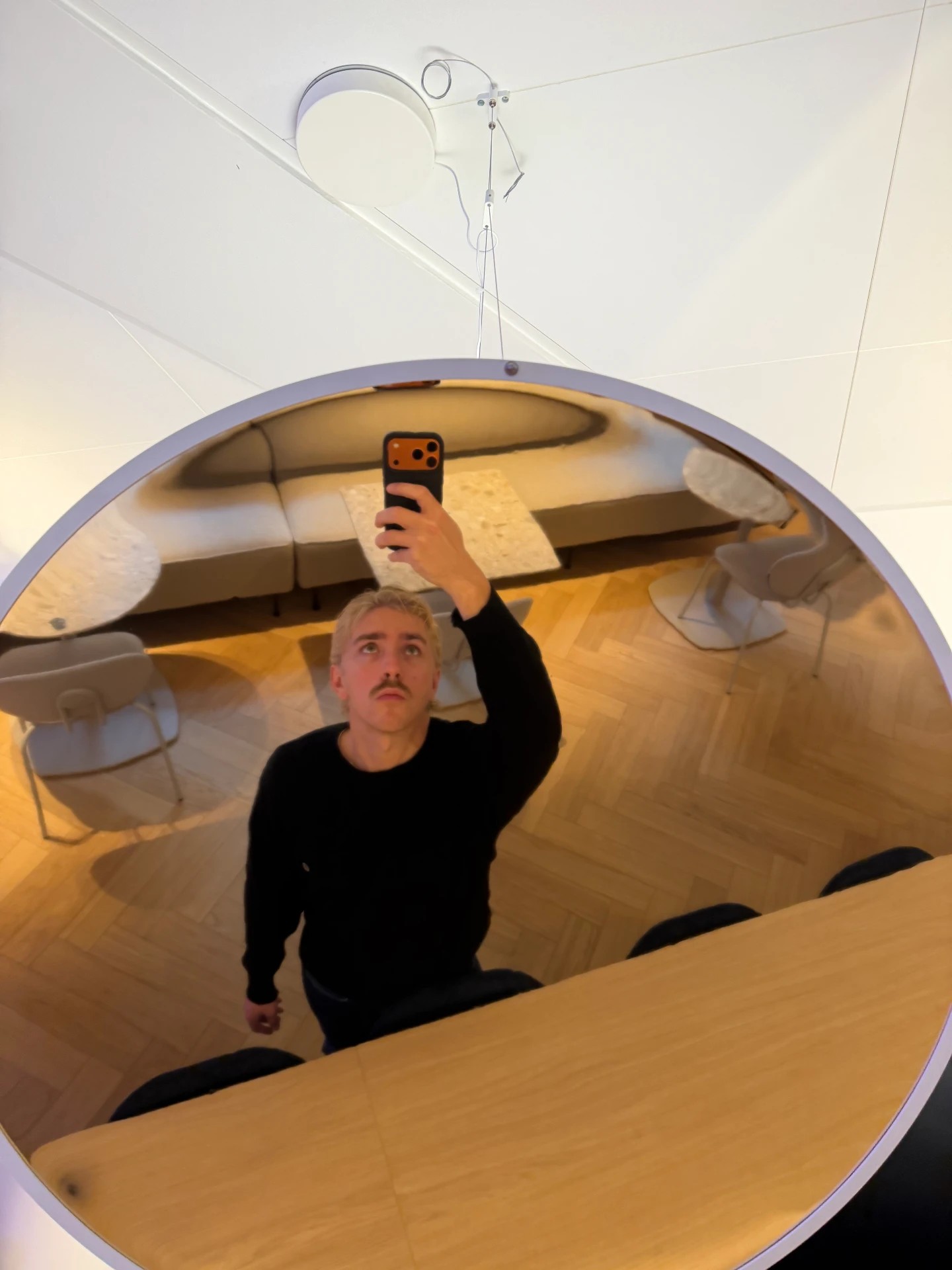 Henry taking an overhead mirror selfie in a wood-floored interior